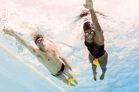 man-en-vrouw-zwemmend-in-zwembad-met-pull-buoy-tussen-benen.jpg